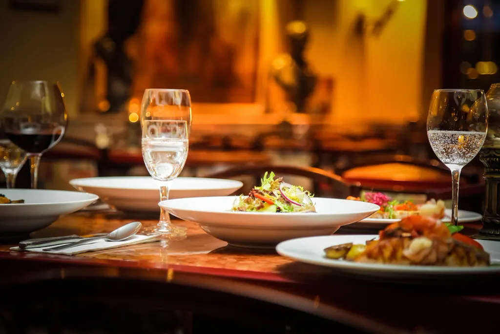 A warmly lit dinner table set with plates and wine glasses