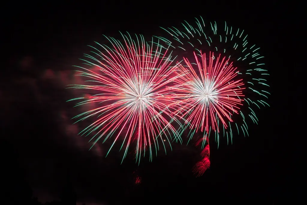 Red and green fireworks bursting in the night sky